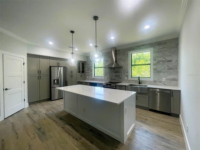 kitchen with crown molding, wall chimney exhaust hood, a sink, stainless steel appliances, and backsplash