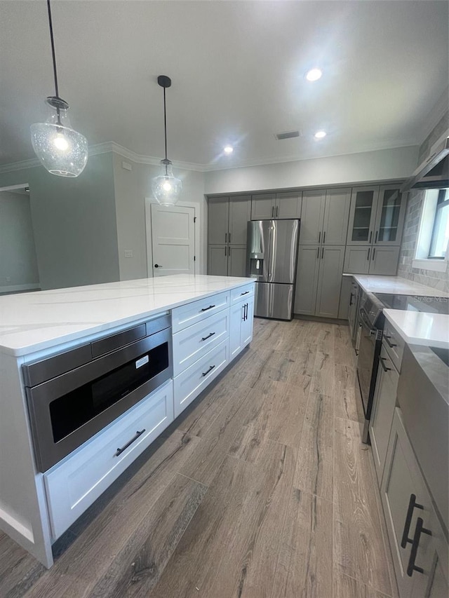 kitchen featuring gray cabinets, light wood-style flooring, visible vents, appliances with stainless steel finishes, and hanging light fixtures