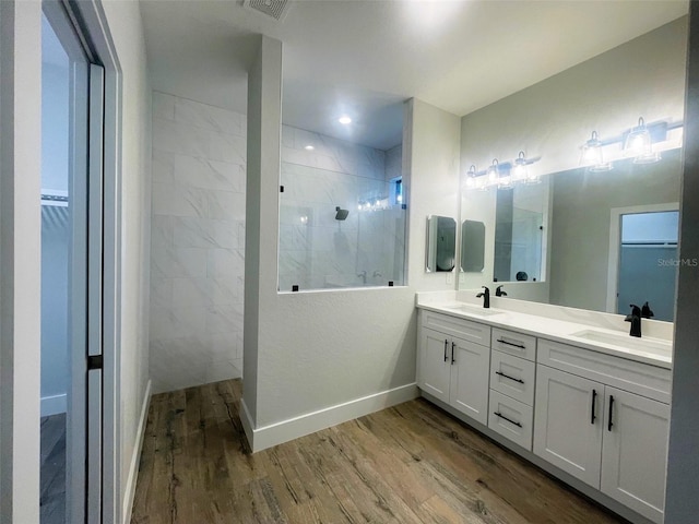 full bathroom with a sink, a walk in shower, double vanity, and wood finished floors