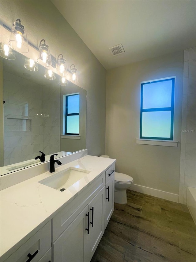 bathroom featuring visible vents, toilet, a shower, vanity, and wood finished floors