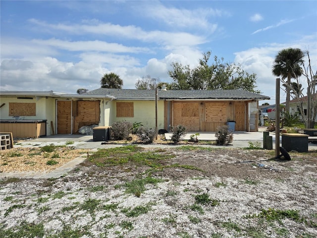 back of property with stucco siding, a hot tub, and a patio