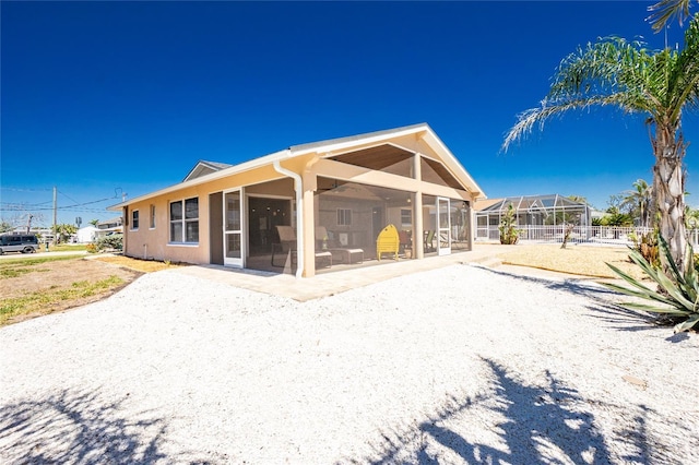 back of house featuring stucco siding and a lanai