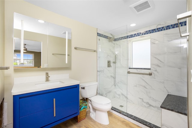 bathroom with a marble finish shower, visible vents, toilet, and wood finished floors