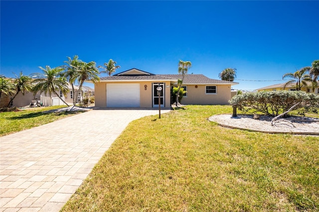 ranch-style home with decorative driveway, a garage, a front yard, and stucco siding