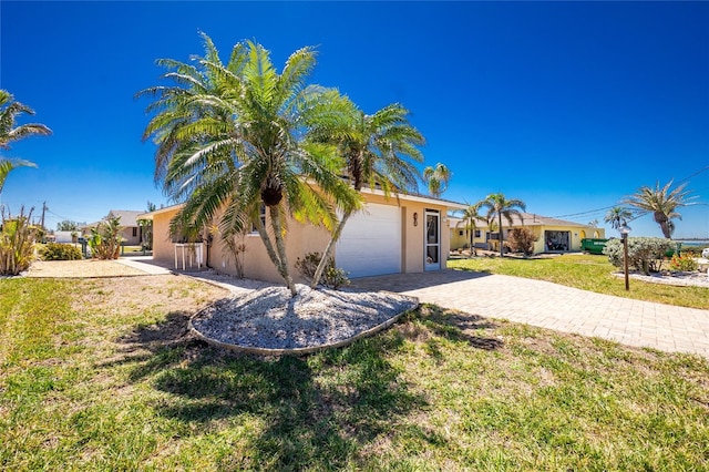 view of front of home featuring a front lawn, decorative driveway, a garage, and stucco siding