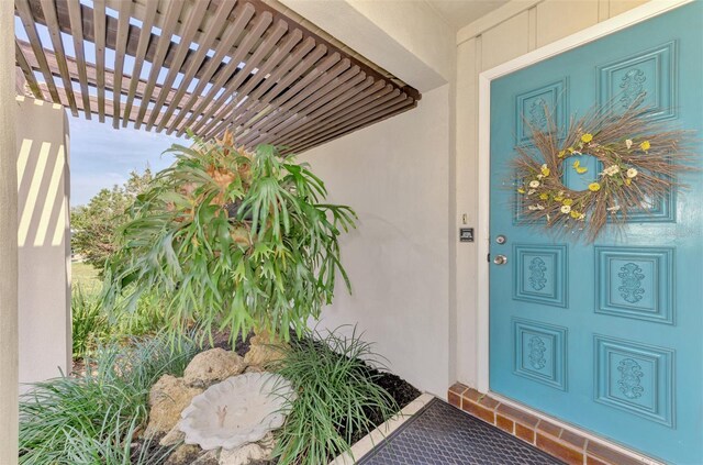 property entrance featuring stucco siding and a pergola