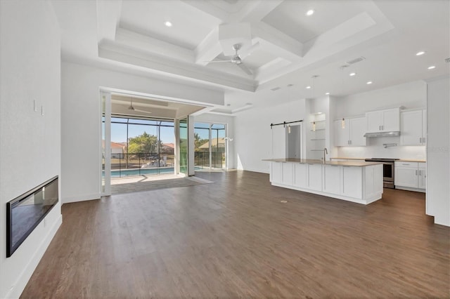 unfurnished living room with a sink, dark wood-style floors, coffered ceiling, and ceiling fan