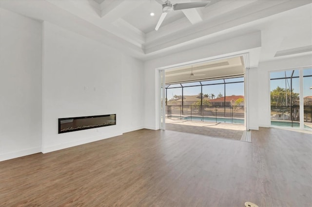 unfurnished living room with wood finished floors, a glass covered fireplace, a healthy amount of sunlight, and ceiling fan