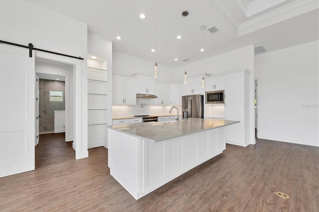 kitchen with white cabinets, visible vents, appliances with stainless steel finishes, a sink, and a large island
