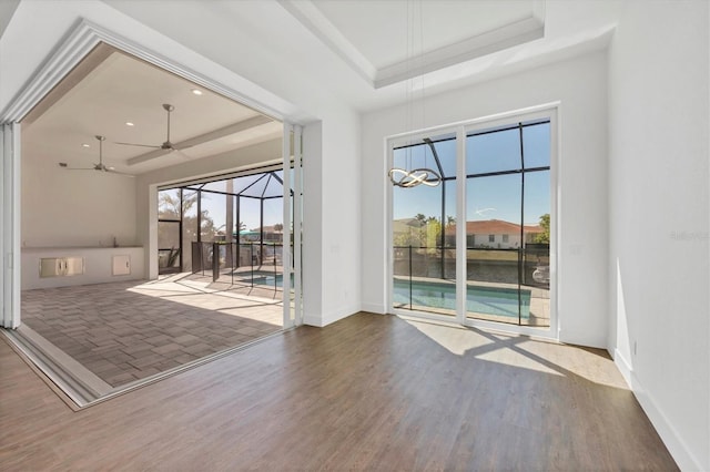 unfurnished room featuring baseboards, a tray ceiling, wood finished floors, and a ceiling fan