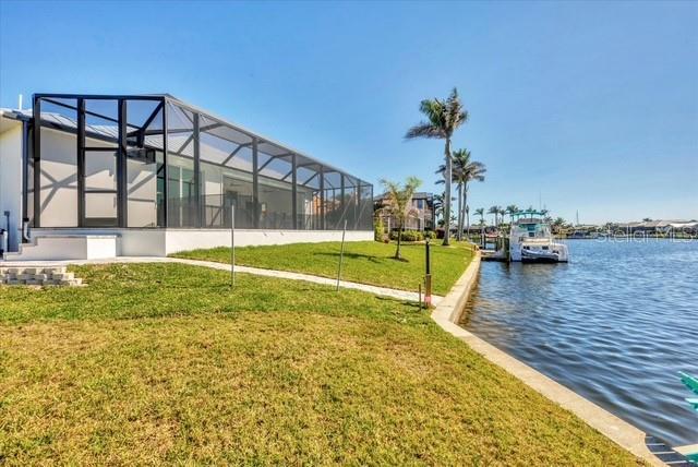 view of dock with a water view, a lanai, and a lawn