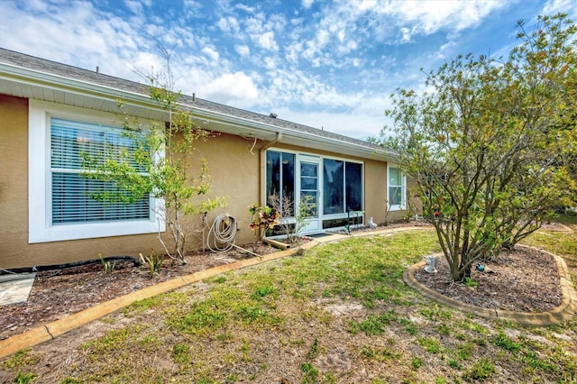 rear view of property featuring stucco siding and a lawn