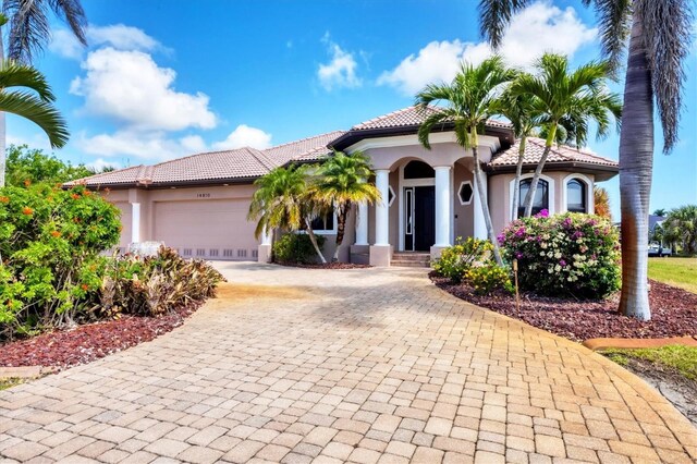 14810 Ingraham Blvd, Port Charlotte, FL 33981 - mediterranean / spanish-style house featuring stucco siding, decorative driveway, an attached garage, and a tiled roof