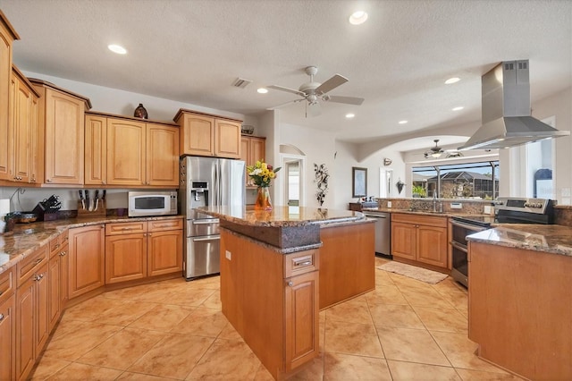 14810 Ingraham Blvd, Port Charlotte, FL 33981 - kitchen featuring stainless steel appliances, a ceiling fan, island exhaust hood, a kitchen island, and dark stone countertops