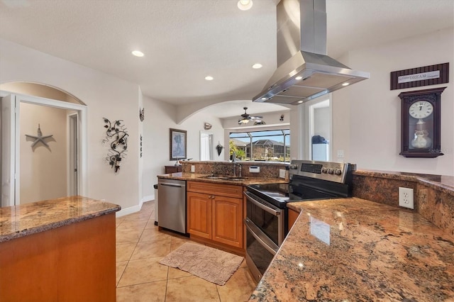 14810 Ingraham Blvd, Port Charlotte, FL 33981 - kitchen with stainless steel appliances, a sink, island range hood, brown cabinets, and dark stone countertops