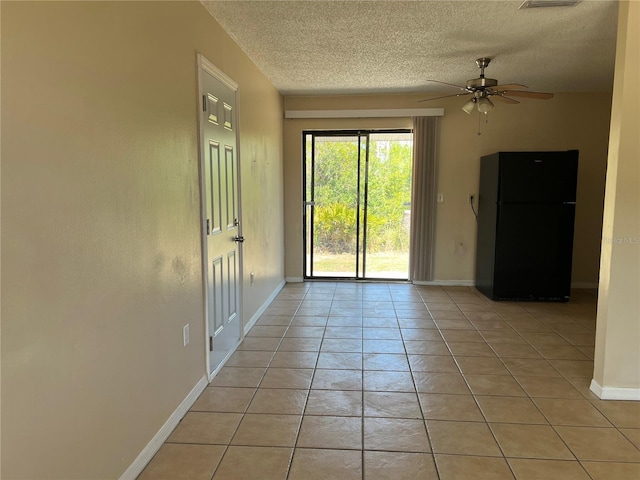 spare room with baseboards, a ceiling fan, a textured ceiling, and light tile patterned floors