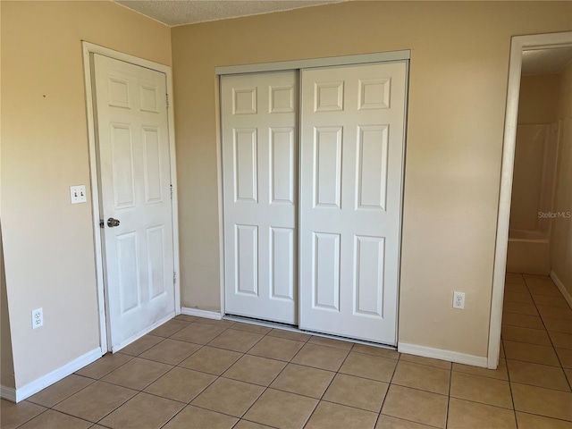 unfurnished bedroom with baseboards, a closet, and light tile patterned flooring