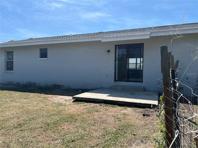 rear view of property featuring a yard and stucco siding