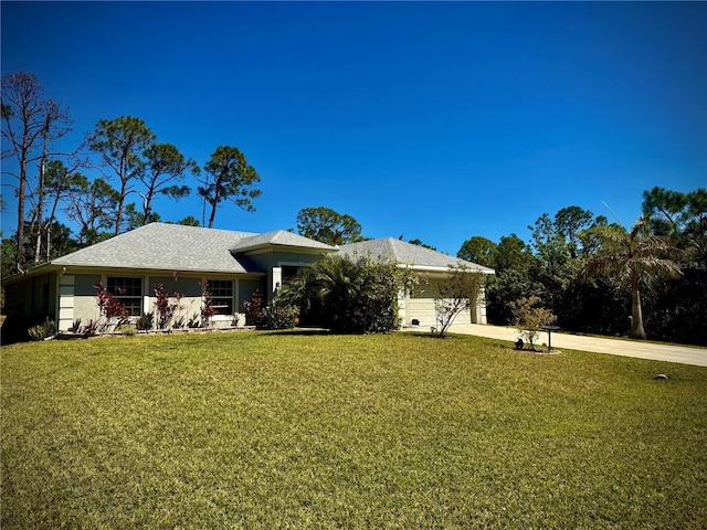 rear view of property with a yard, an attached garage, and concrete driveway