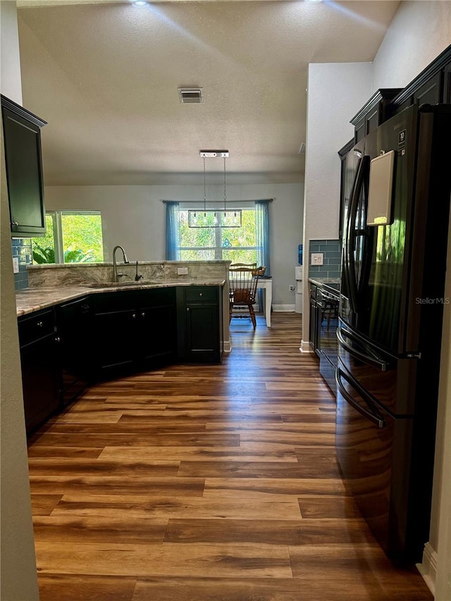 kitchen with a sink, dark cabinetry, a peninsula, dark wood finished floors, and black appliances