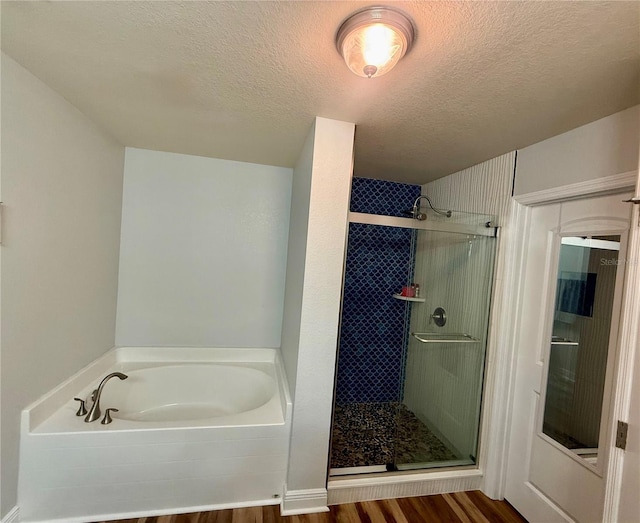 bathroom with a stall shower, wood finished floors, a bath, and a textured ceiling