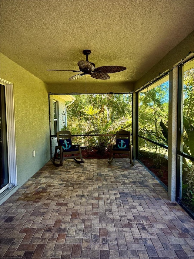unfurnished sunroom with ceiling fan