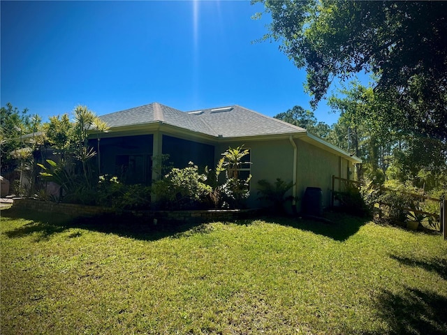 view of side of property featuring roof with shingles, stucco siding, and a yard