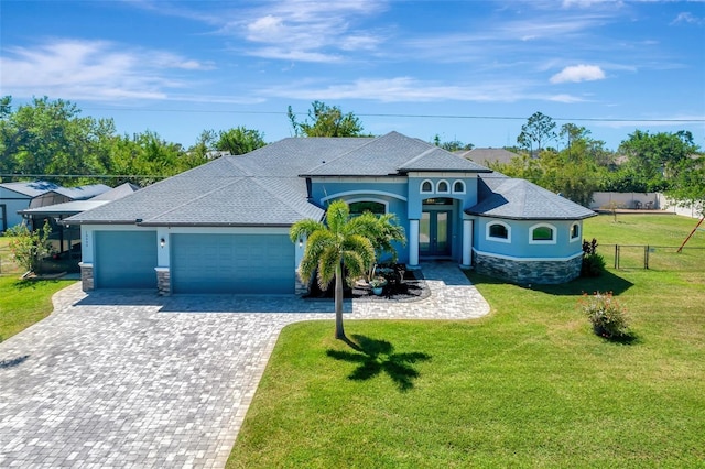 view of front of house with driveway, a front lawn, stone siding, fence, and a garage
