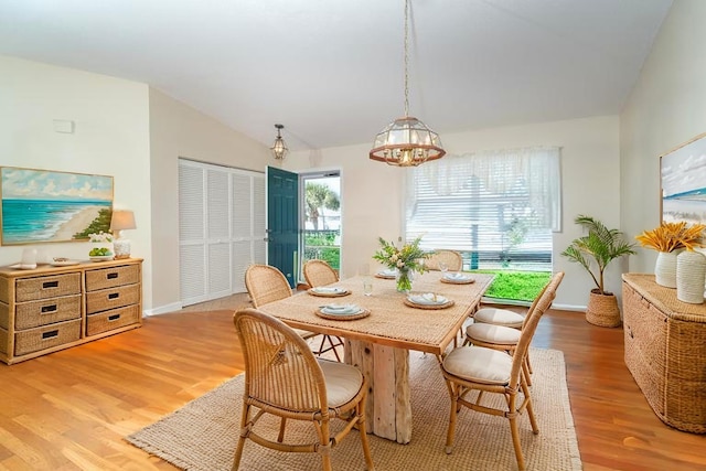 dining area featuring lofted ceiling, light wood finished floors, baseboards, and a notable chandelier