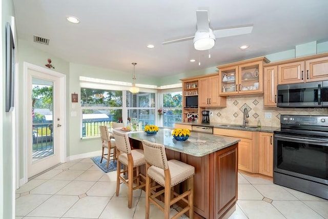 kitchen with stainless steel appliances, visible vents, a sink, decorative backsplash, and a breakfast bar area
