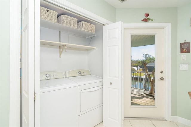 washroom with a water view, baseboards, separate washer and dryer, laundry area, and light tile patterned floors