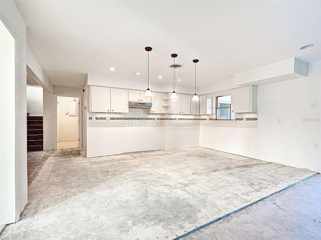 kitchen featuring backsplash, white cabinets, under cabinet range hood, decorative light fixtures, and visible vents