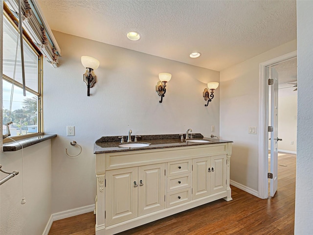 bathroom featuring a sink, baseboards, wood finished floors, and a textured ceiling