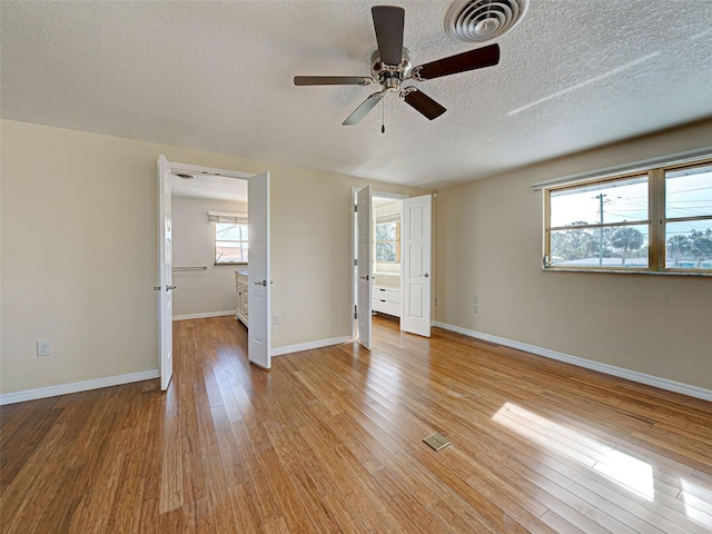 unfurnished bedroom with a textured ceiling, light wood finished floors, baseboards, and visible vents