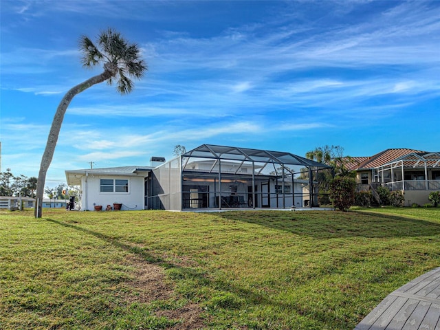 rear view of property with a lanai and a lawn