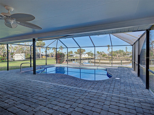 outdoor pool featuring a patio area, glass enclosure, a yard, and a ceiling fan