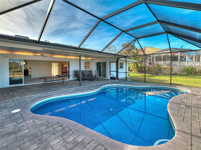 outdoor pool with a patio area, a ceiling fan, and glass enclosure