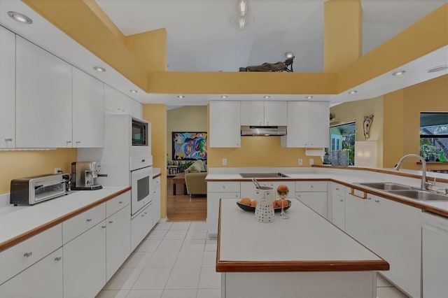 850 Van Gogh Rd, Englewood, FL 34223 - kitchen with under cabinet range hood, white appliances, light countertops, light tile patterned floors, and white cabinets
