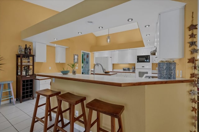 850 Van Gogh Rd, Englewood, FL 34223 - kitchen with white appliances, white cabinetry, light tile patterned floors, a peninsula, and decorative light fixtures