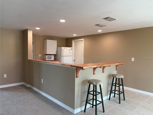 3415 Gulf Ln, Rotonda West, FL 33947 - kitchen with wooden counters, white appliances, a breakfast bar, recessed lighting, and baseboards