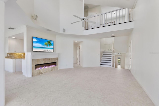 768 Seaboard Line Ln, Boca Grande, FL 33921 - unfurnished living room with tile patterned floors, stairway, a ceiling fan, a towering ceiling, and a premium fireplace