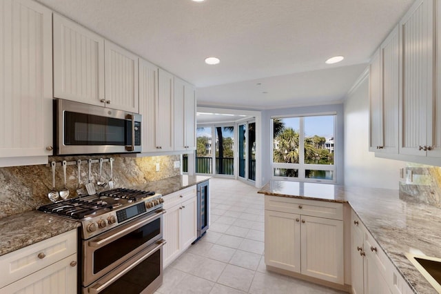 768 Seaboard Line Ln, Boca Grande, FL 33921 - kitchen with stainless steel appliances, beverage cooler, backsplash, light stone counters, and white cabinetry