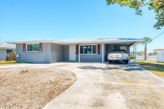 ranch-style house with concrete driveway, an attached carport, concrete block siding, and fence