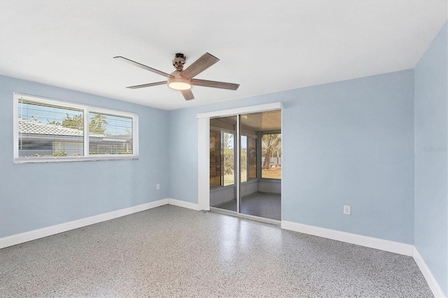 spare room featuring plenty of natural light, baseboards, speckled floor, and ceiling fan