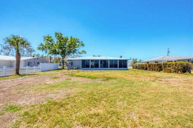 back of property with a yard, a sunroom, and fence