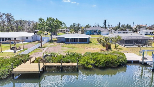 dock area with fence, a yard, a residential view, and a water view