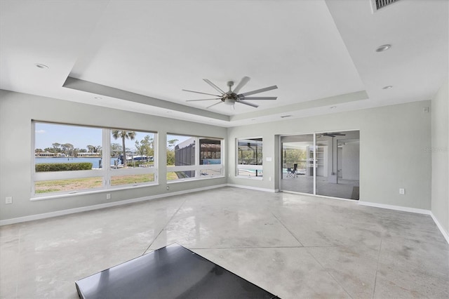 empty room with baseboards, concrete flooring, and a raised ceiling