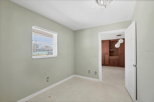 spare room with baseboards and light carpet