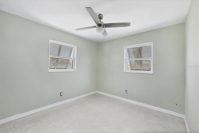 unfurnished room featuring a ceiling fan, baseboards, and speckled floor