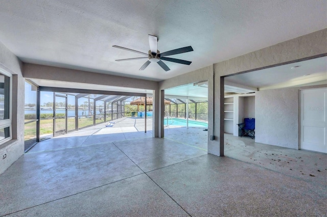 view of patio / terrace with an outdoor pool, a ceiling fan, and glass enclosure